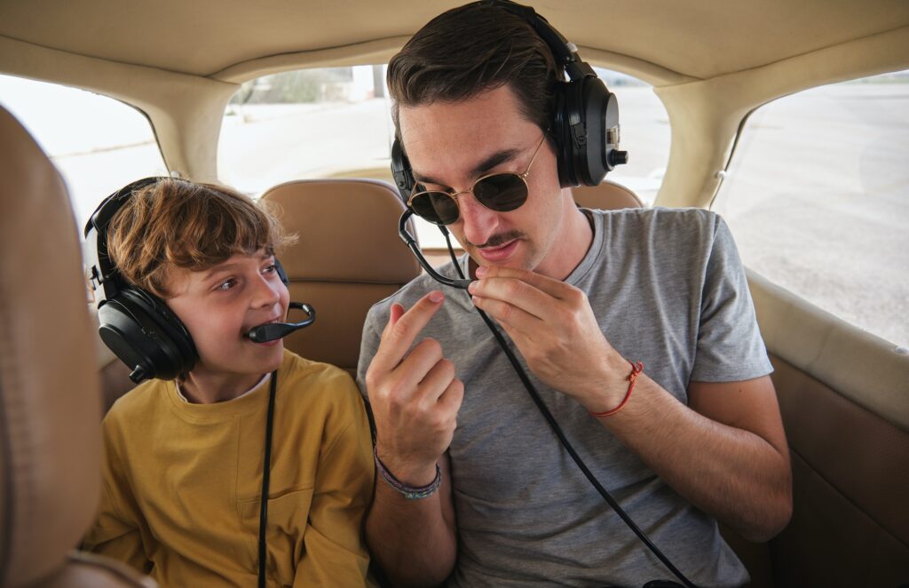 young man instructing happy kid before flight in small aircraft 1.jpg