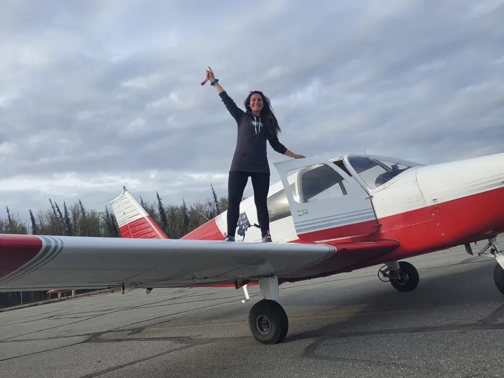 lady celebrating on plane wing after passing pilot license check flight