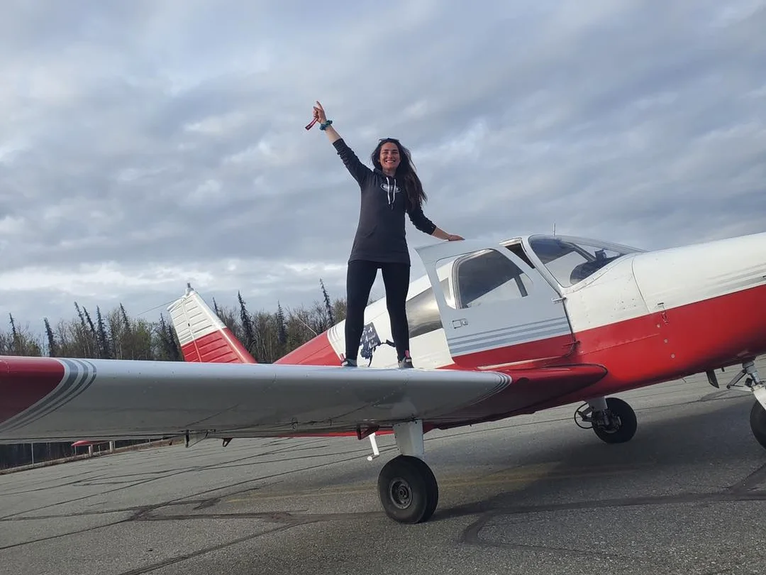 lady celebrating on plane wing after passing pilot license check flight