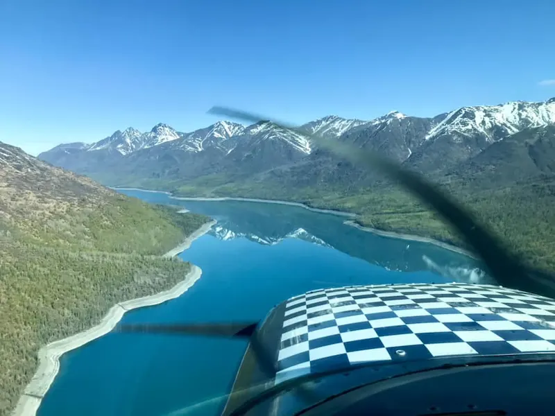 checkerboard plane over river and snow capped mountains winter flying