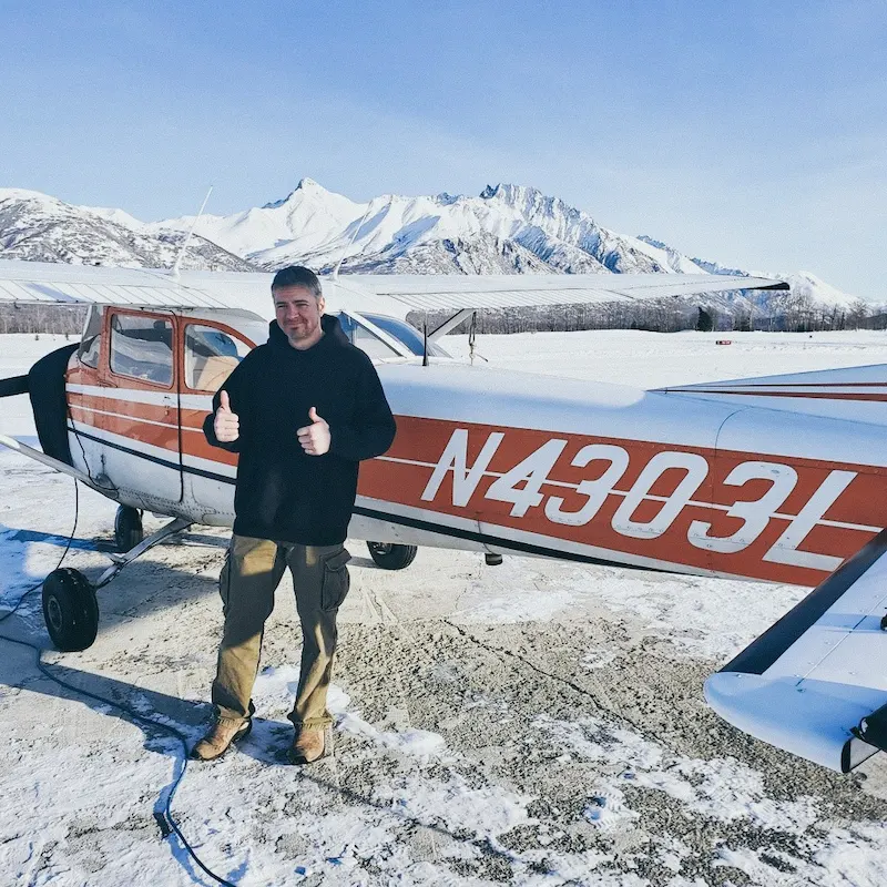 man with plane thumbs up snowy mountain backdrop winter flying